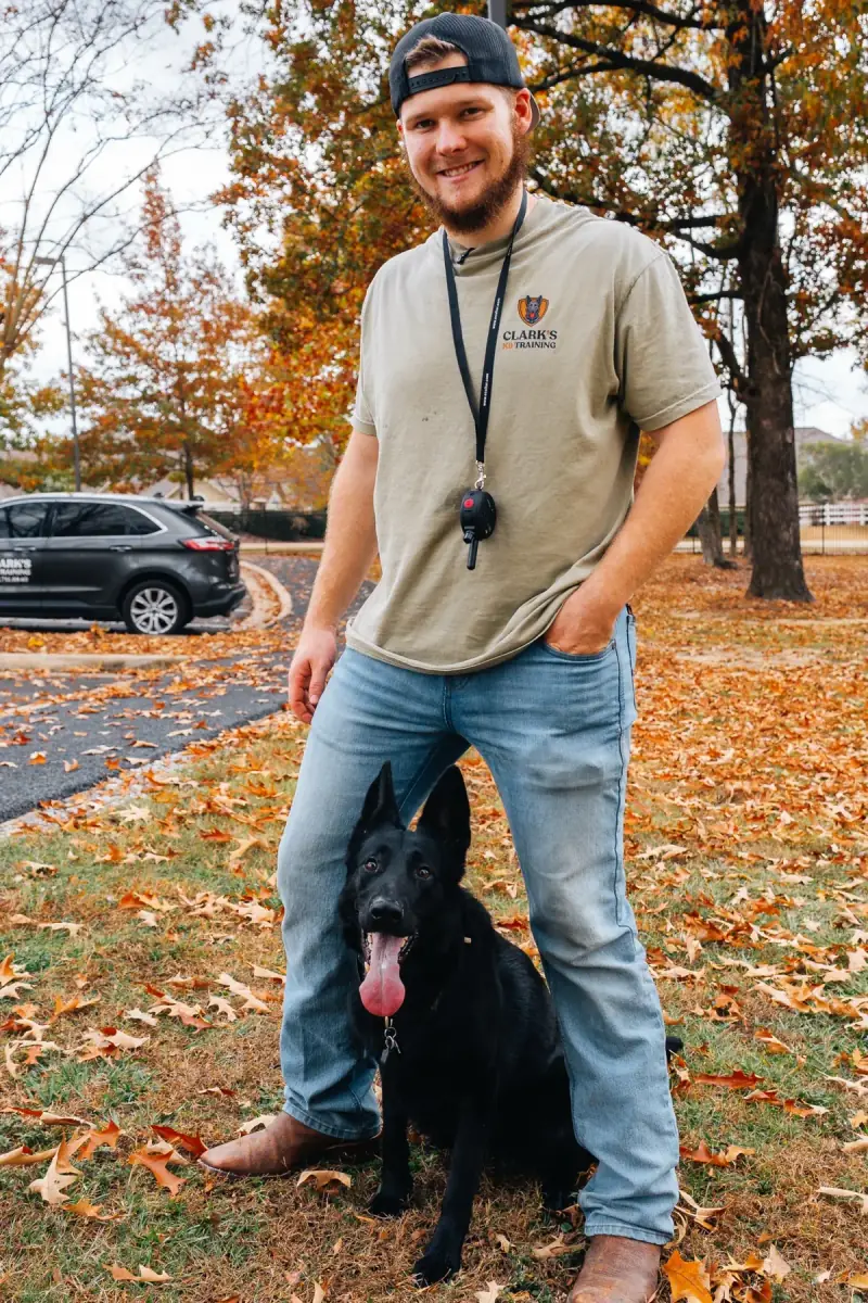 Bailey Clark of Clark's Canine Training standing with a black German Shepherd in a Brandon, Mississippi park