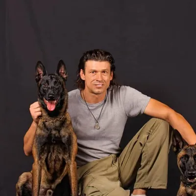 Ivan Balabanov seated with two Belgian Malinois