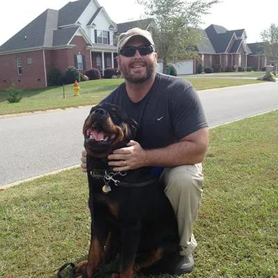 Larry Krohn kneeling with a Rottweiler