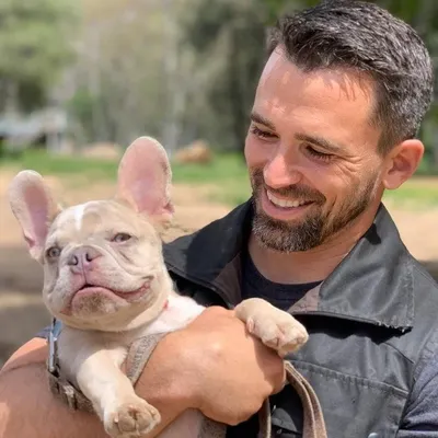 Nate Schoemer smiling while holding a French bulldog puppy